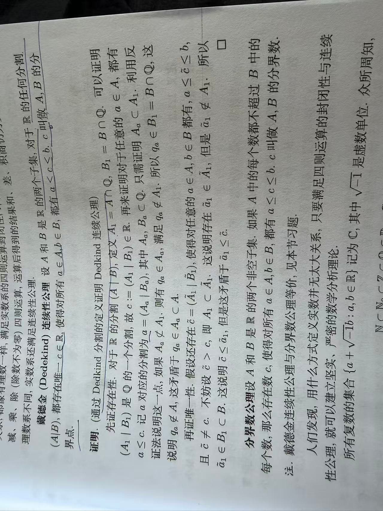 A mathematical analysis textbook page containing the Dedekind continuity axiom and its boundary-number proof