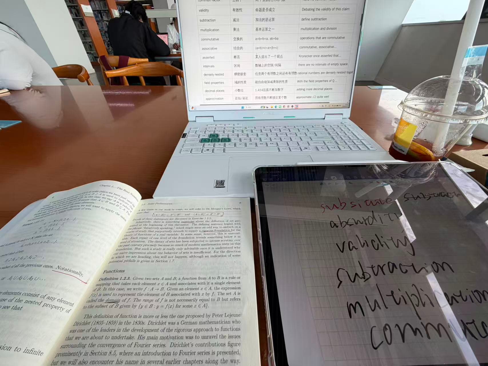 An analysis glossary on a computer beside an English textbook and handwritten vocabulary notes