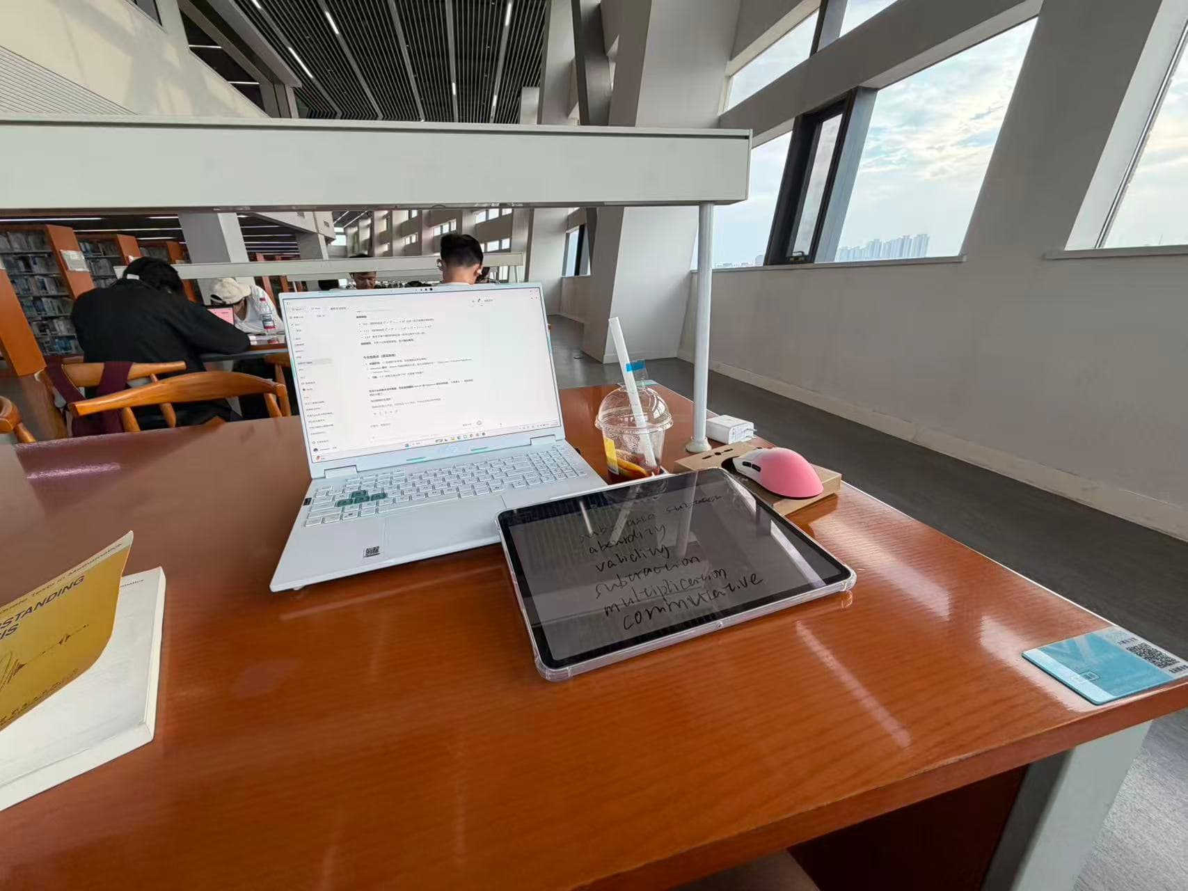 A laptop, tablet, and study materials on a library desk