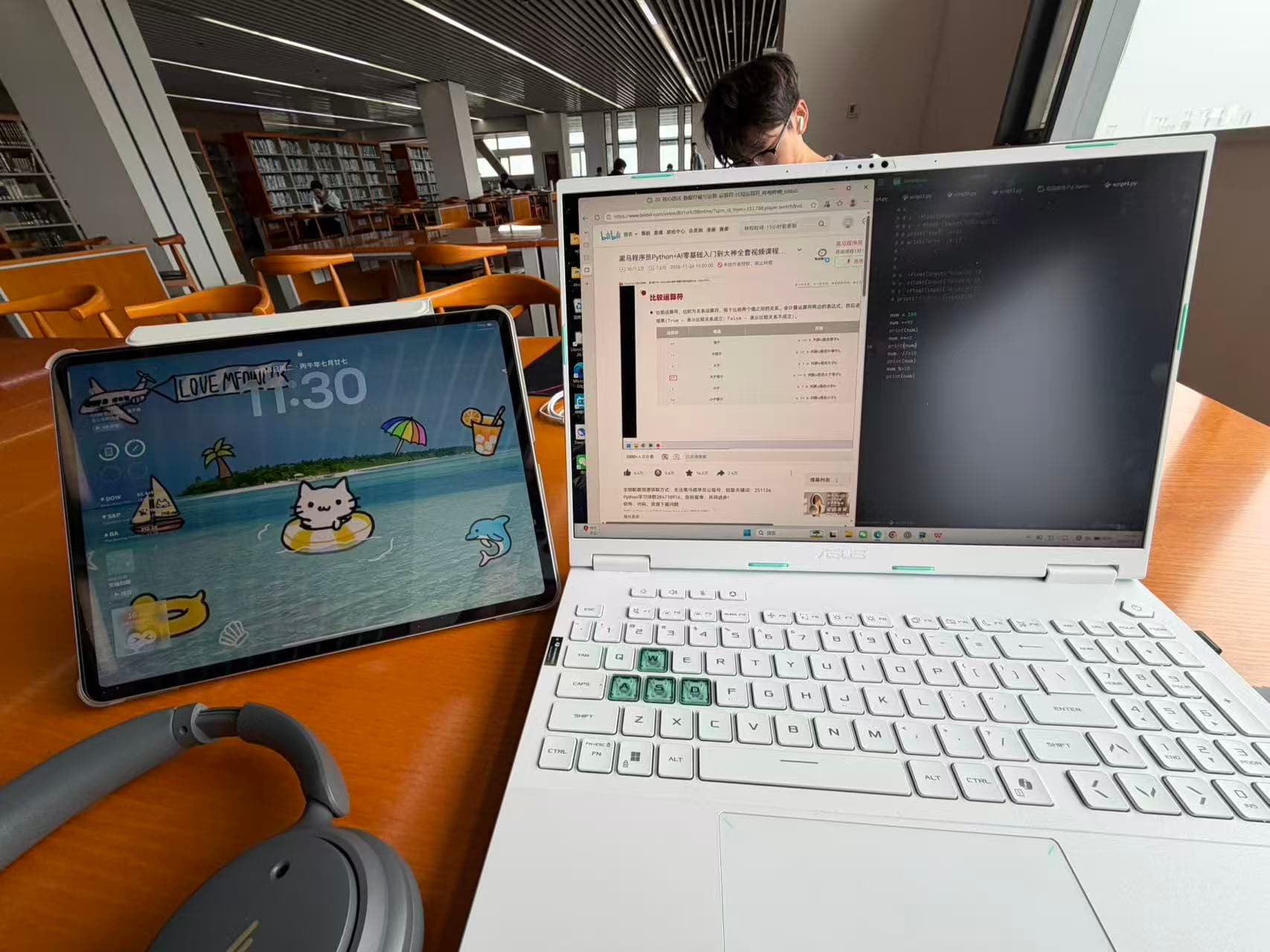 A tablet, headphones, and a laptop running a Python lesson and code on a library desk