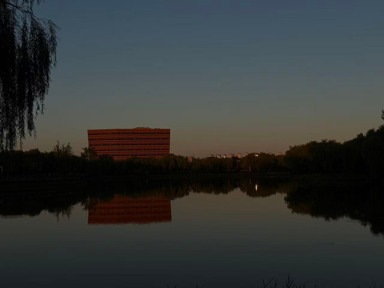 A red building and the fading evening sky reflected in a still lake