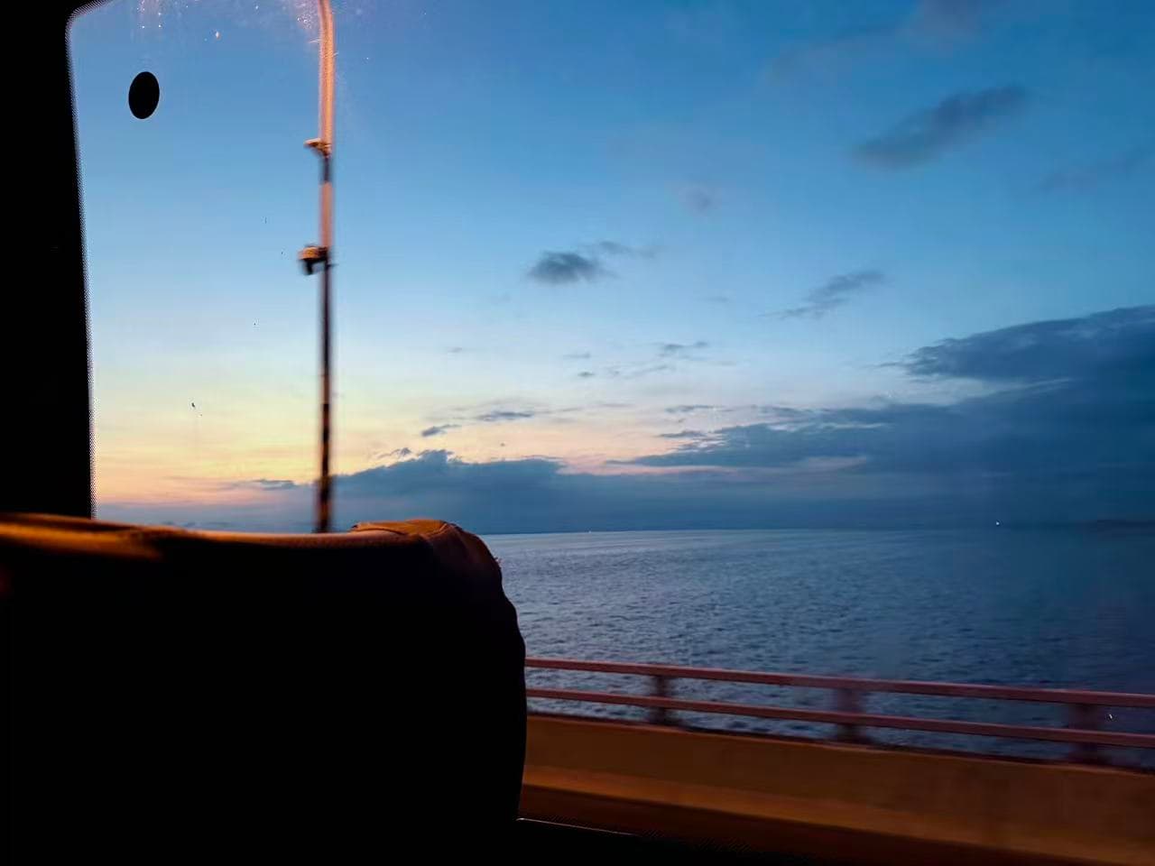 The sea and evening sky seen through the window on the journey home