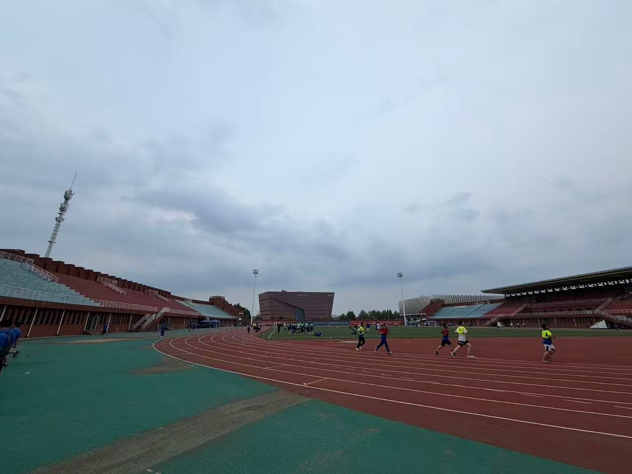 Students taking their physical fitness test on the school track beneath an overcast sky