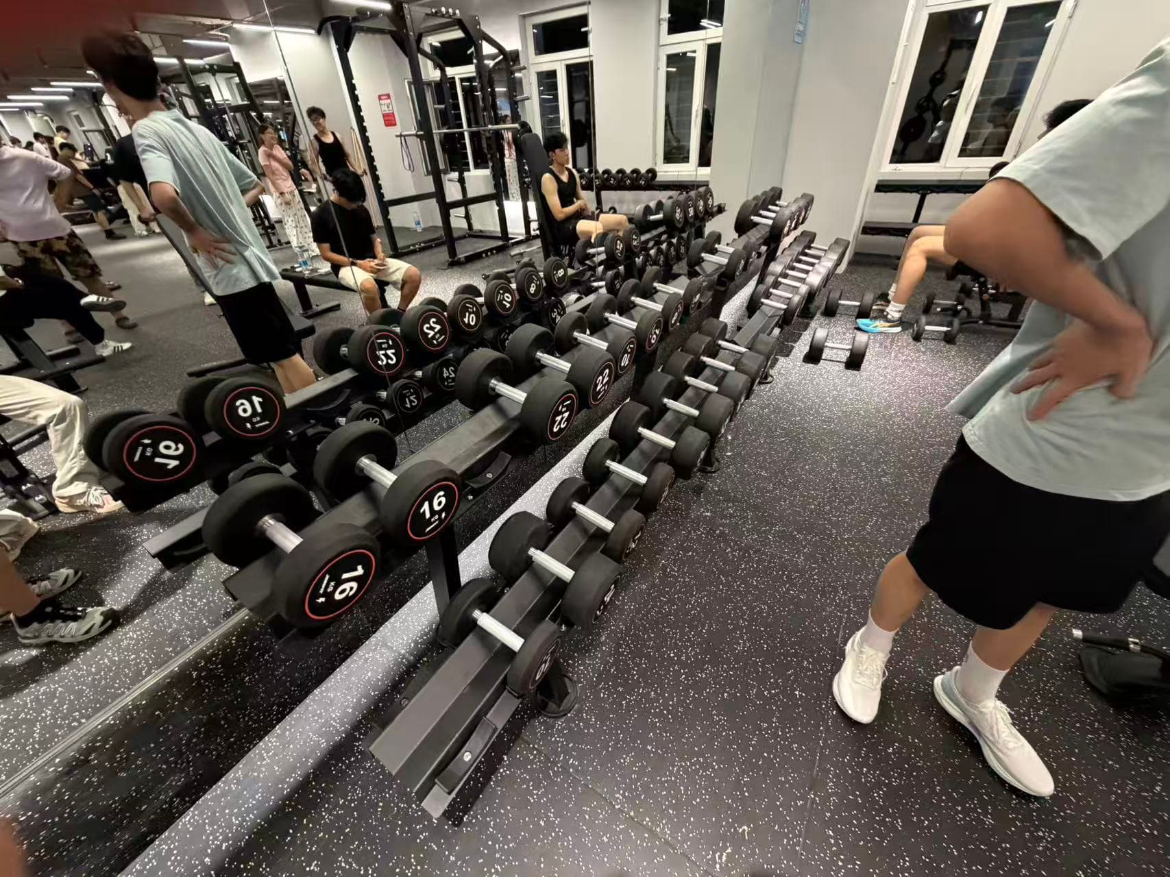 Rows of dumbbells in the gym, with a student resting nearby