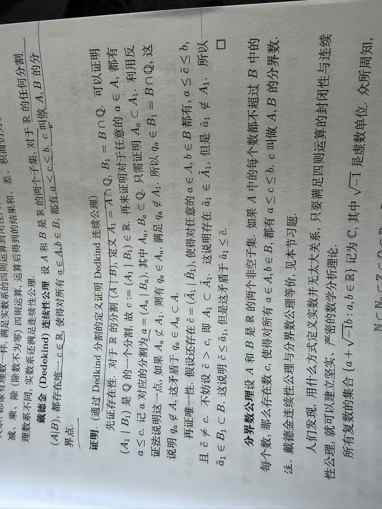 A mathematical analysis textbook page containing the Dedekind continuity axiom and its boundary-number proof