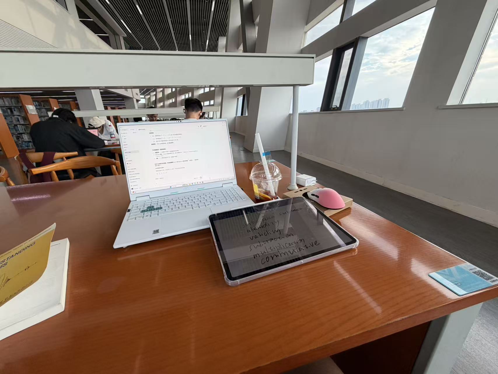 A laptop, tablet, and study materials on a library desk
