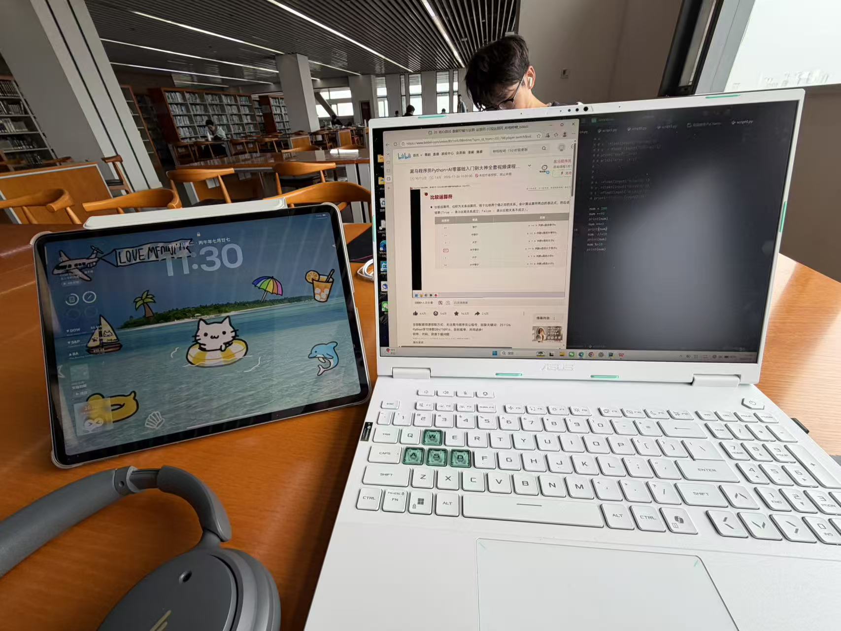 A tablet, headphones, and a laptop running a Python lesson and code on a library desk