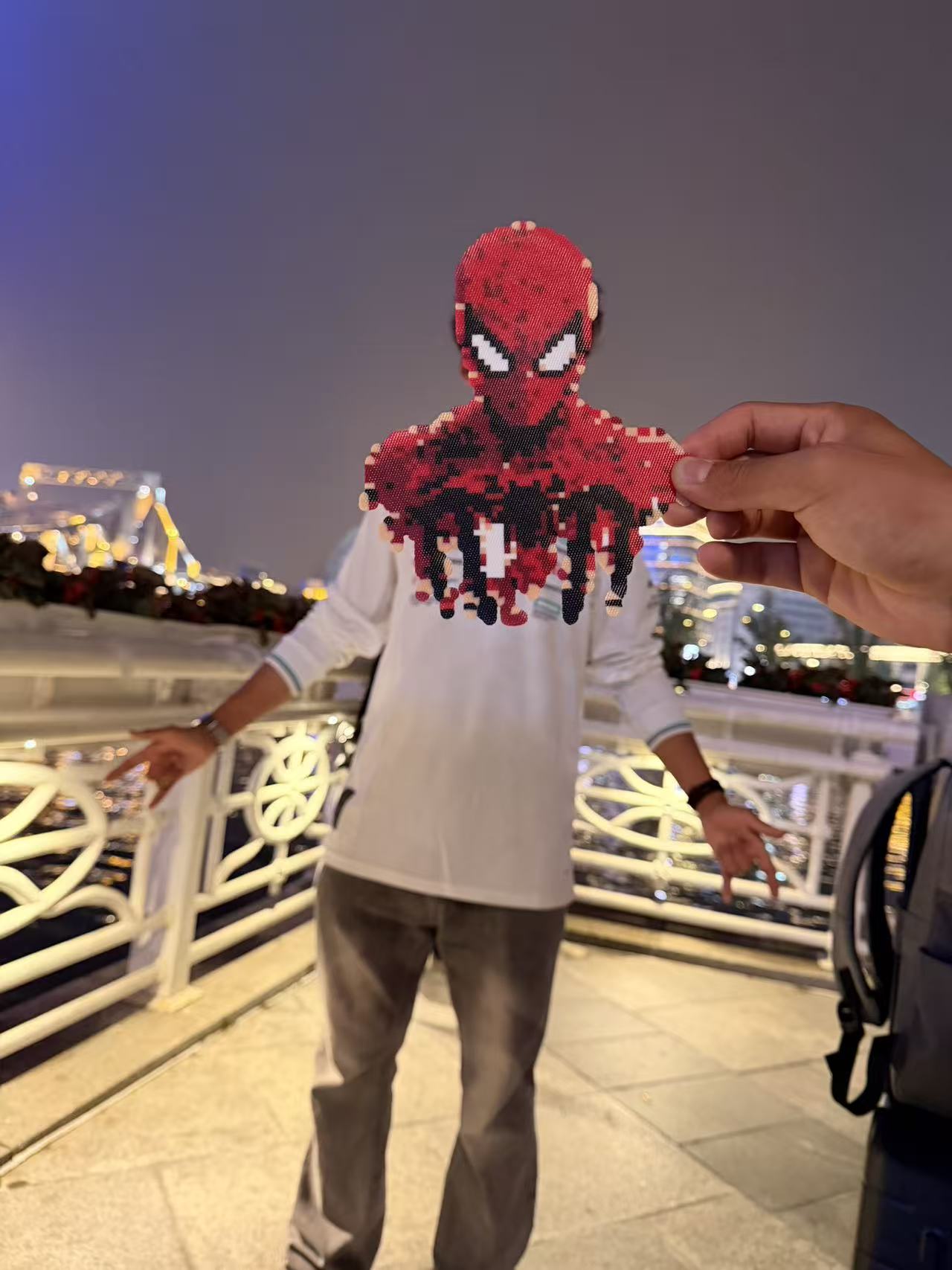 A playful forced-perspective photo with a Spider-Man bead figure beside the Haihe River