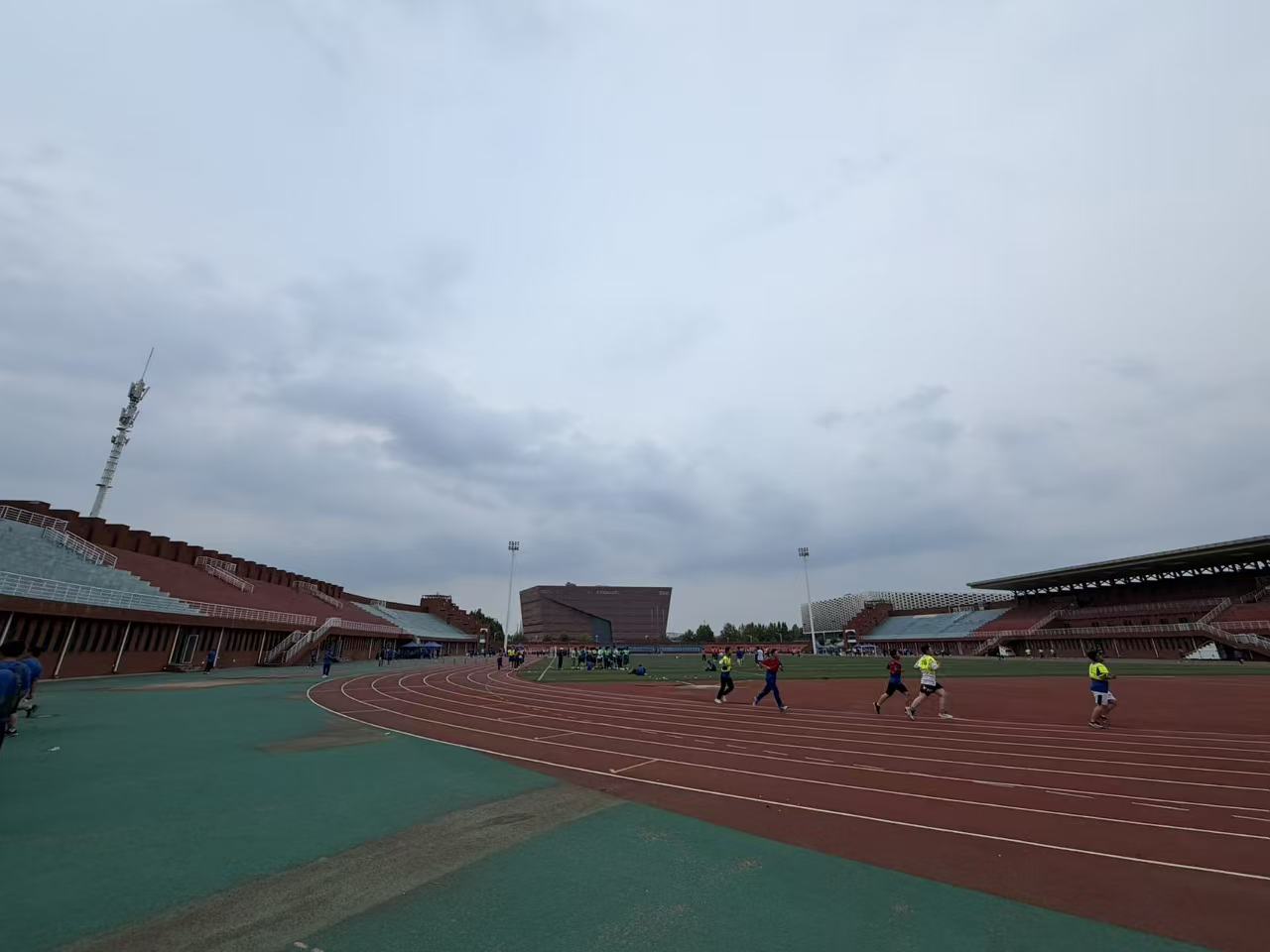 Students taking their physical fitness test on the school track beneath an overcast sky
