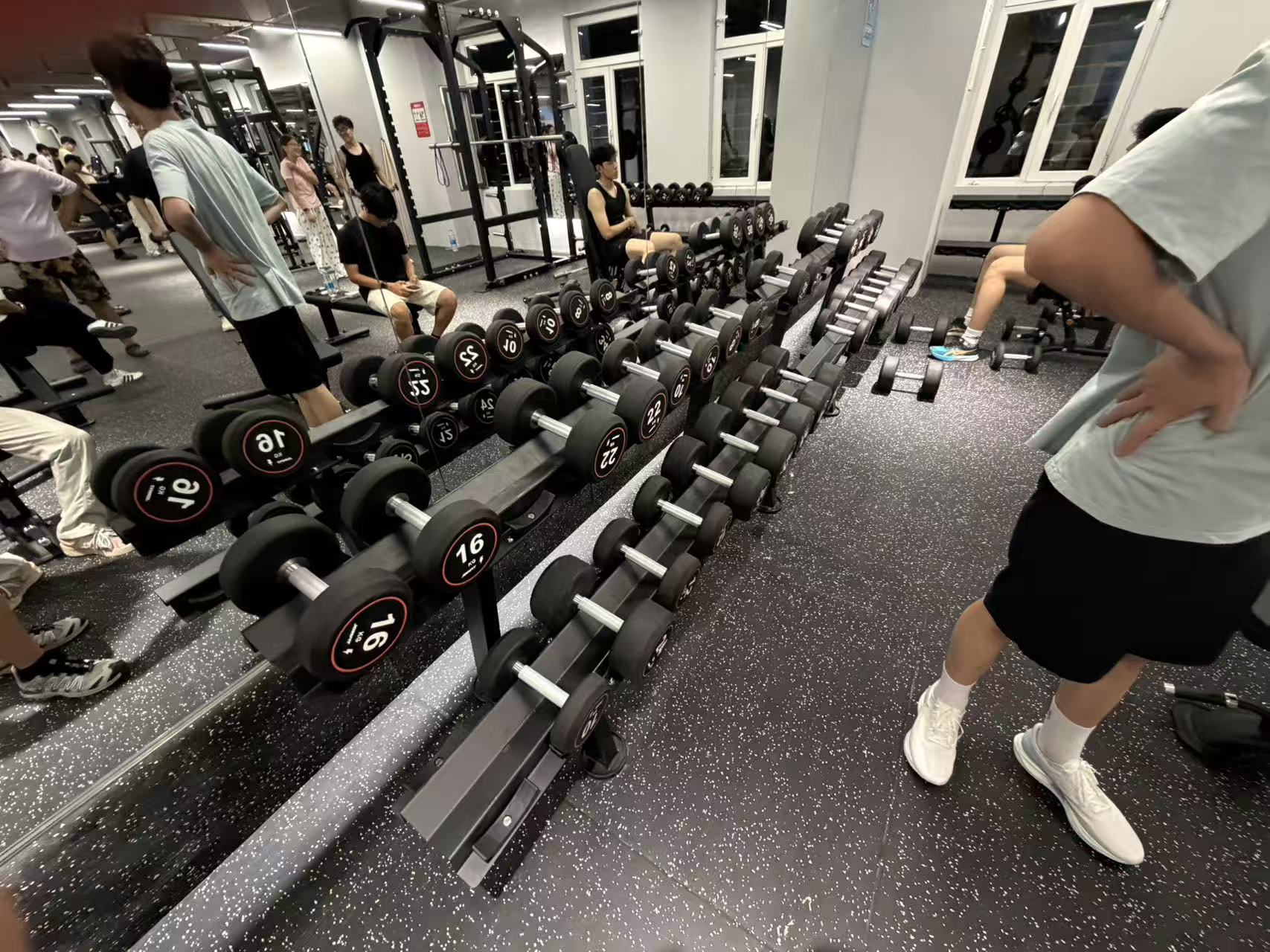Rows of dumbbells in the gym, with a student resting nearby