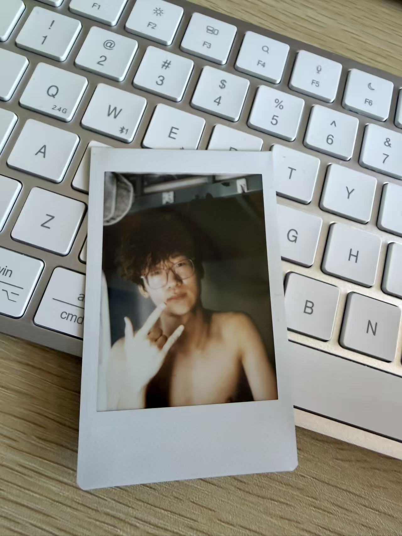 A slightly blurred instant portrait resting on a white keyboard